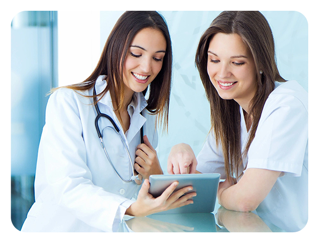 Two women in lab coats looking at a tablet.