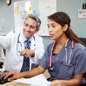 A doctor and nurse are sitting at the desk.