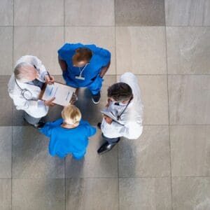 Three doctors are standing on the floor and one is holding a clipboard.